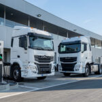 Deux tracteurs routiers électriques blancs de 44 tonnes stationnés sur une plateforme logistique française, avec des bornes de recharge rapide visibles dans la lumière matinale.